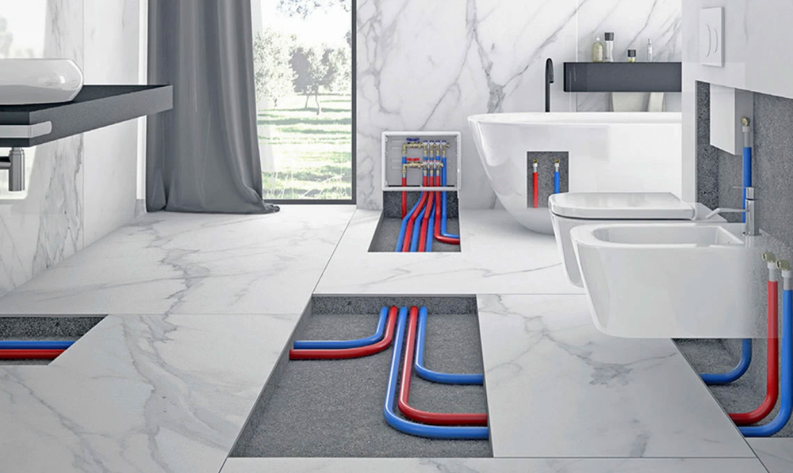 Interno di un bagno moderno con tubature idrauliche visibili nel pavimento, includendo una vasca da bagno, un lavabo e un bidet, in un ambiente elegante con pareti di marmo.